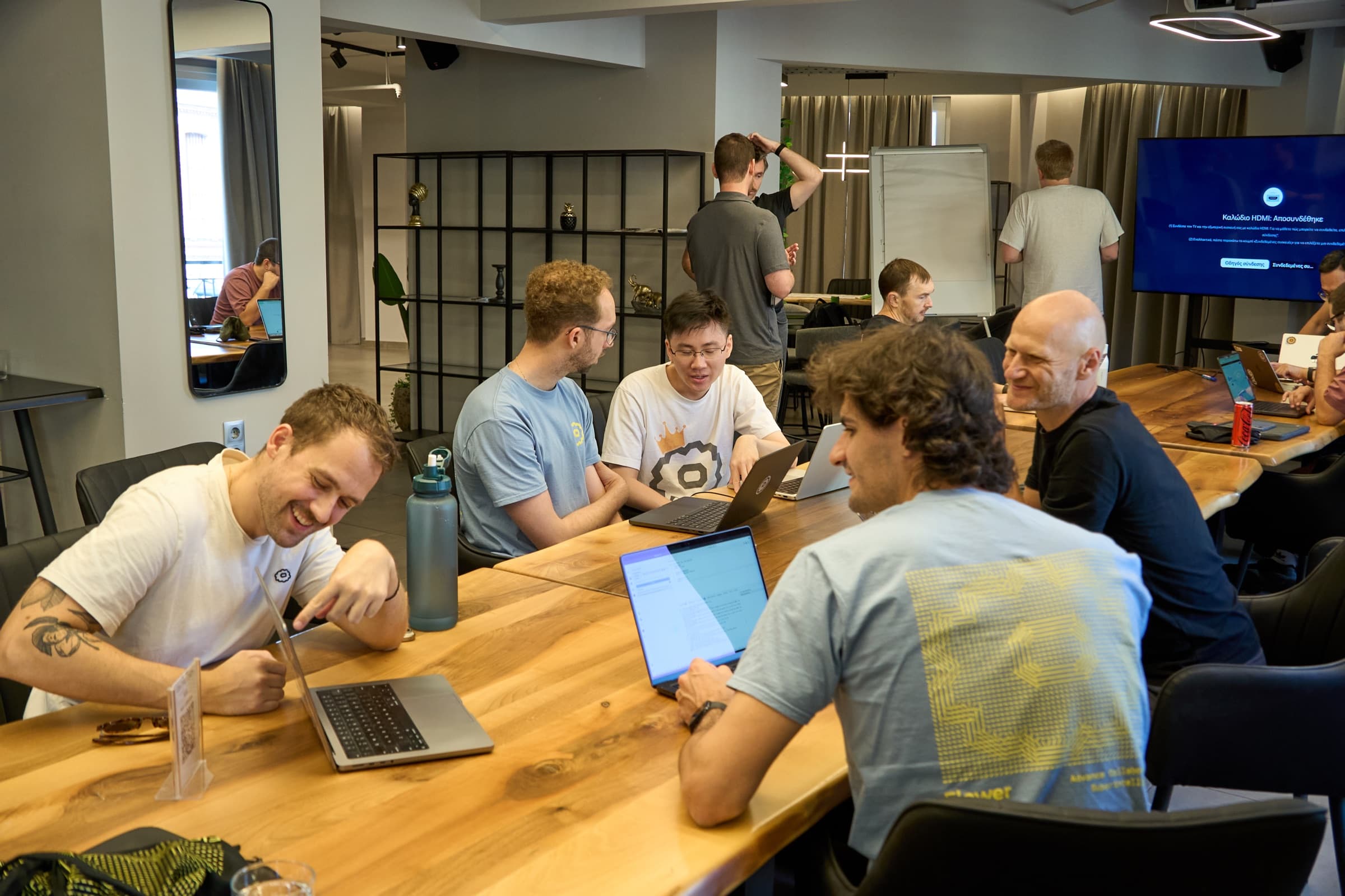 Hackathon participants collaborating around a table with their laptops